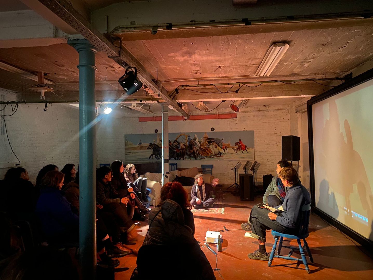 Two people in front of a film projection screen with audience interacting