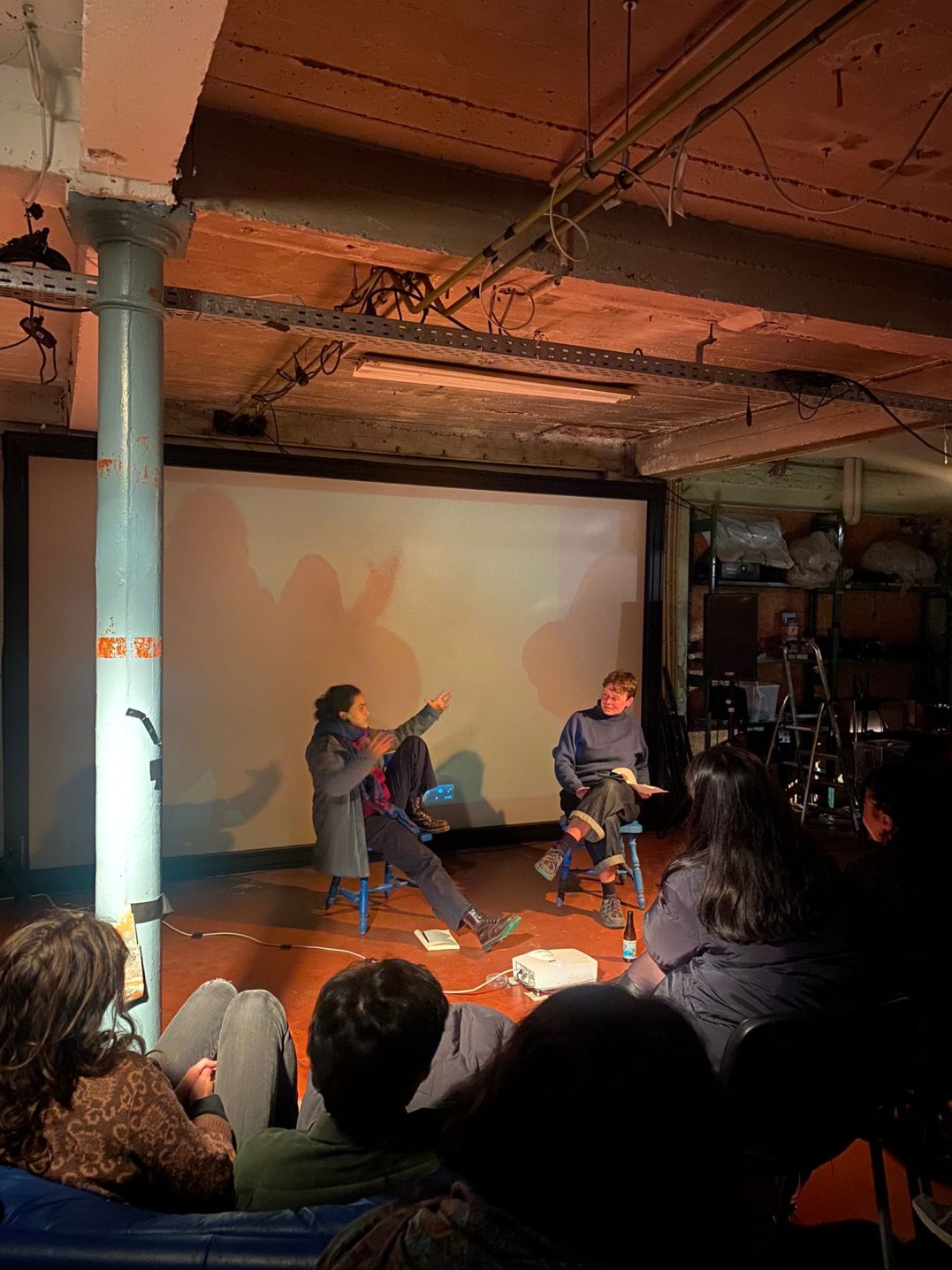 Two people in front of film projection screen talking